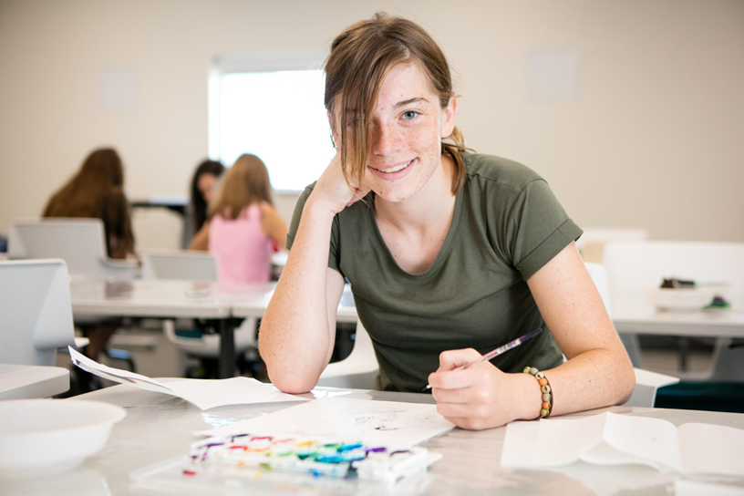 girl in green shirt sitting at desk