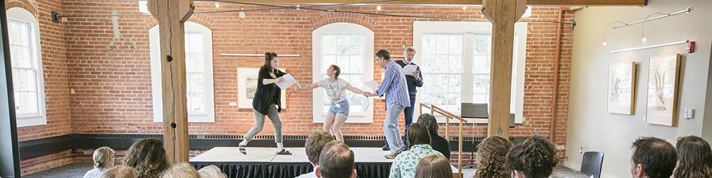 Theatre students act out a scene as their classmates watch